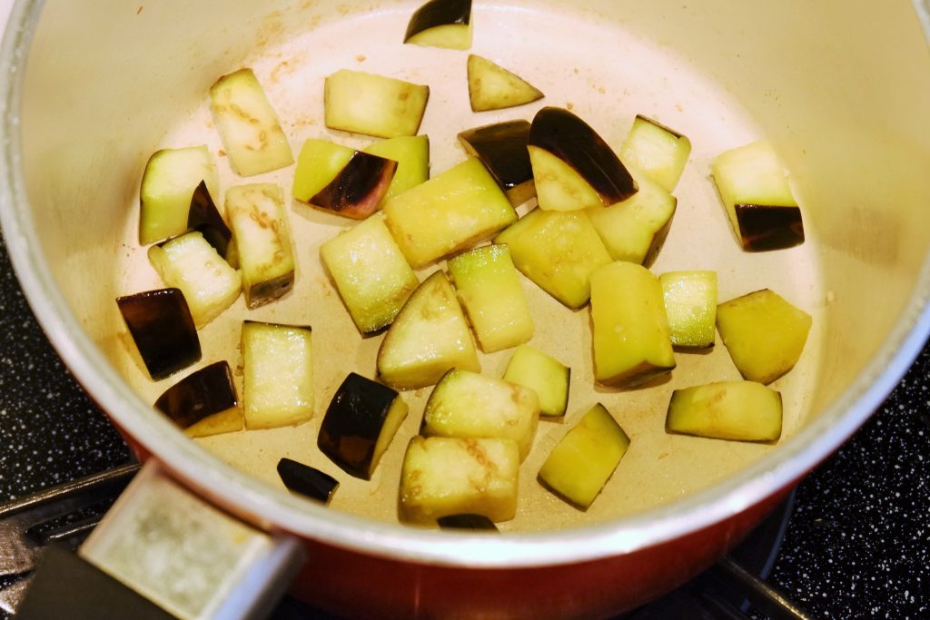 ③鍋ににんにく、オリーブオイルを入れ、温まってきたらなすを入れて炒める。